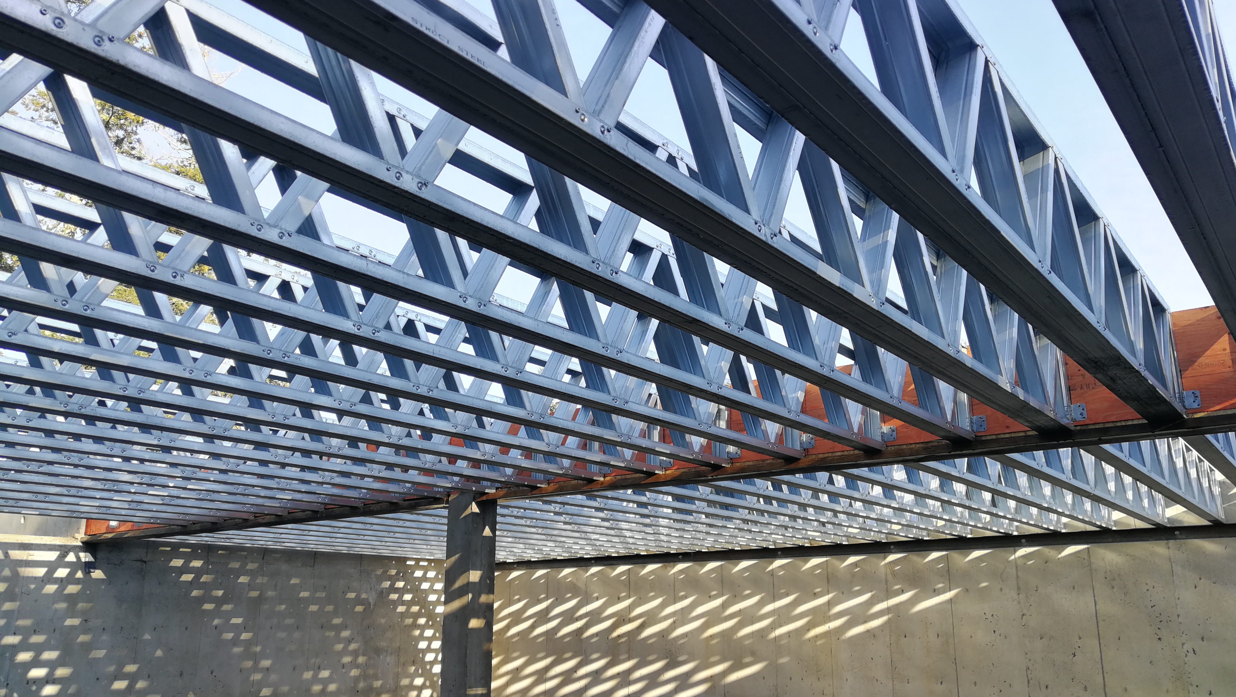 Steel trusses casting precise shadow patterns on a concrete wall