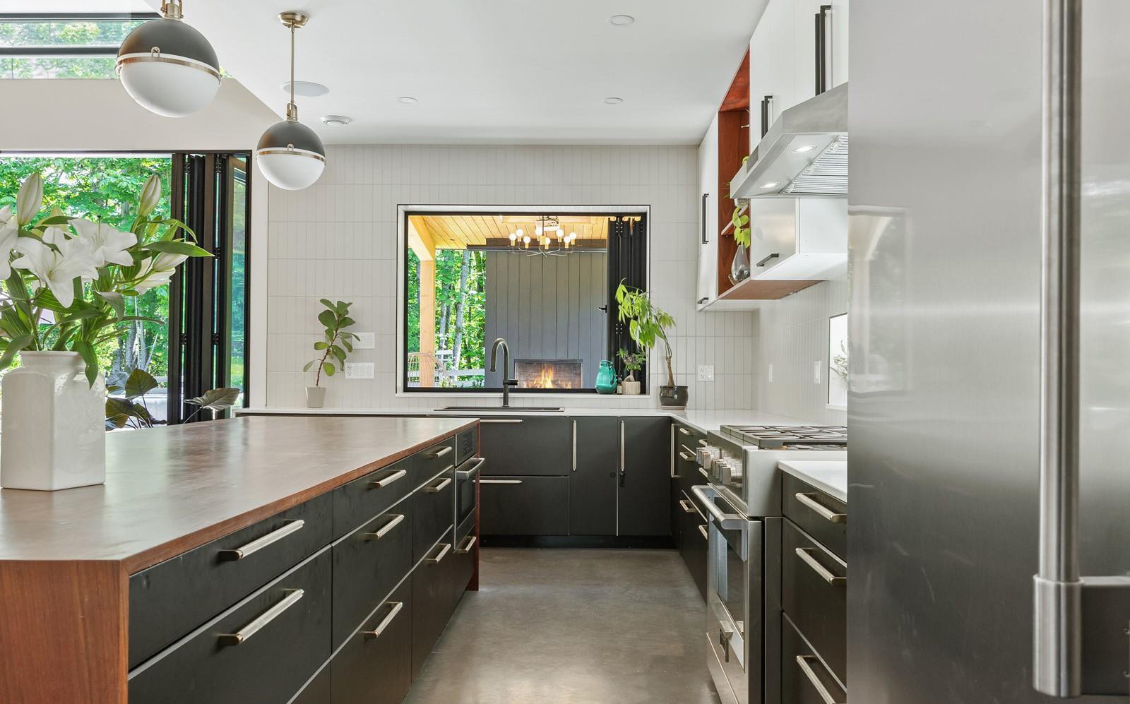 Kitchen with matte black cabinetry and window onto the outdoor fireplace